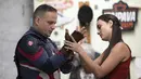 Polisi militer Everaldo Pinto, mengenakan kostum Captain America dengan bantuan istrinya di Petropolis, Rio de Janeiro, Brasil, Kamis (15/4/2021). Dalam aksinya, Pinto membagikan kotak berisi produk pembersih dan masker untuk mencegah paparan corona pada anak-anak. (AP Photo/Silvia Izquierdo)