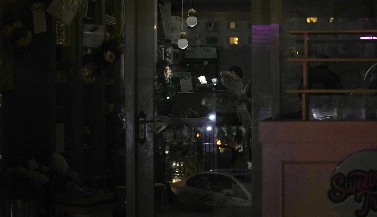 Seorang penjaga toko menggunakan lampu baterai di tokonya selama pemadaman listrik nasional, di Islamabad, Pakistan, Senin, 23 Januari 2023. Listrik padam di semua kota besar, termasuk di Karachi, Islamabad, Lahore dan Peshawar. (AP Photo/K.M. Chaudary)