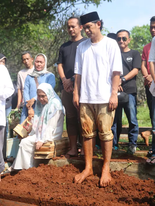 <p>Mengenakan pakaian putih dan mengenakan peci hitam. Sedangkan celananya tampak berlumpur tanah merah. Ibnu Jamil tampak tegar menyaksikan proses pemakaman sang ayah. [Foto: Adrian Putra/Fimela.com]</p>