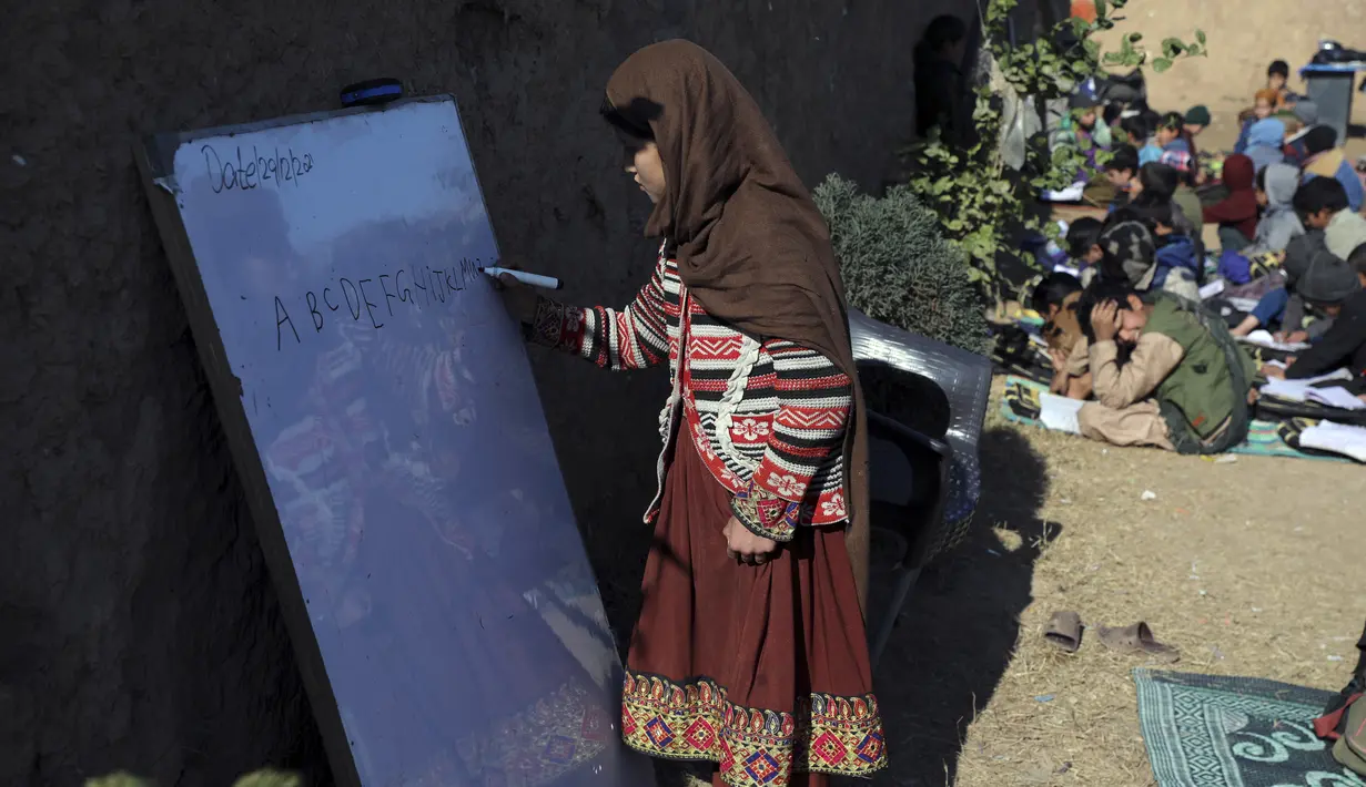 Seorang anak sekolah pengungsi Afghanistan berlatih alfabet Inggris di sebuah sekolah darurat di pinggiran Islamabad, Pakistan, Rabu (29/12/2021). (AP Photo/Rahmat Gul)