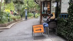 Seorang pria duduk di luar kedai kopi Beatles yang dibuka kembali untuk layanan dibawa pulang (takeaway) di London, Inggris (10/6/2020). Beberapa kedai kopi di Inggris telah dibuka kembali untuk pengiriman atau layanan takeaway dengan mengikuti aturan jaga jarak sosial. (Xinhua/Han Yan)