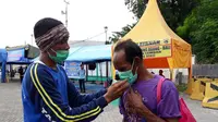 Anggota Taruna Siaga Bencana (Tagana) Provinsi Nusa Tenggara Barat (NTB) membagikan masker kepada para penyintas asal Bali di Pelabuhan Lembar, Lombok Barat, NTB. (Dok: Kemensos)