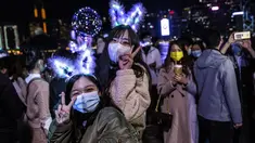 Dua wanita berpose di samping tepi perairan Pelabuhan Victoria di Hong Kong (1/1/2020). Meskipun ada pembatasan virus corona COVID-19 dan kembang api Tahun Baru dibatalkan, orang-orang berkumpul untuk merayakan Tahun Baru. (AFP/Isaac Lawrence)