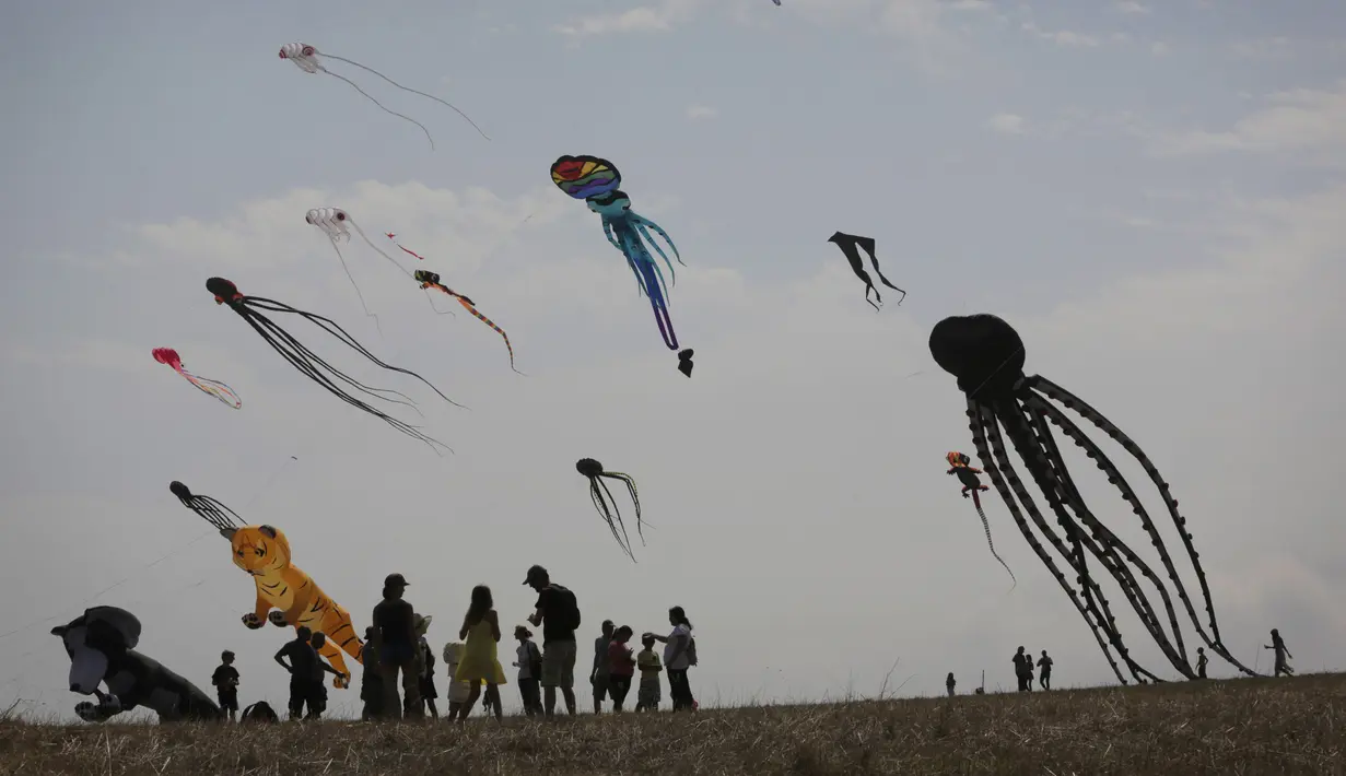 Orang-orang mengambil bagian dalam Varvara Kite Fest di Desa Varvara, pesisir Laut Hitam, Bulgaria, Jumat (27/8/2021). Penyelenggara Varvara Kite Fest Andrey Kulev mengatakan bahwa menerbangkan layang-layang seperti melepaskan semua masalah Anda di langit. (AP Photo/Valentina Petrova)