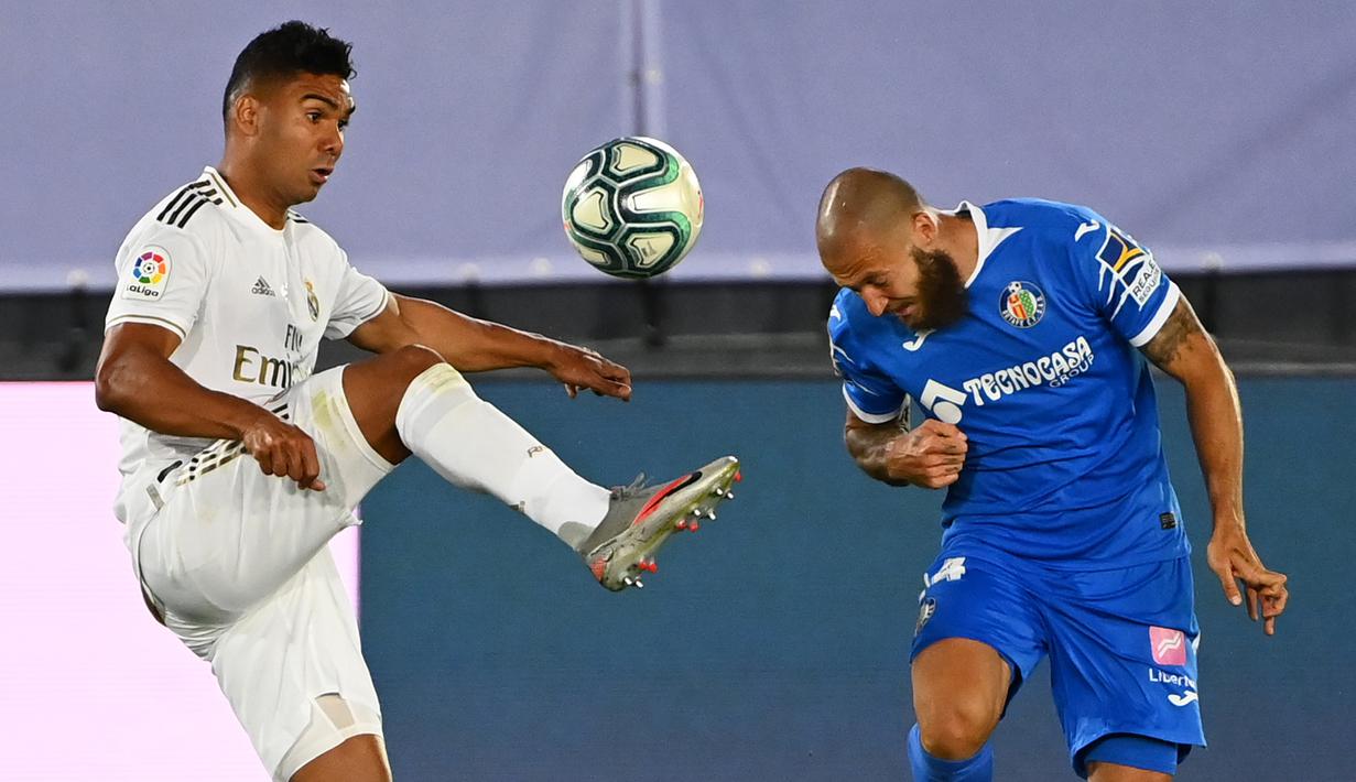 Gelandang Real Madrid, Casemiro, berebut bola dengan gelandang Getafe, David Timor, pada laga lanjutan La Liga pekan ke-33 di Stadion Alfredo Di Stefano, Jumat (3/7/2020) dini hari WIB. Real Madrid menang 1-0 atas Getafe. (AFP/Gabriel Bouys)
