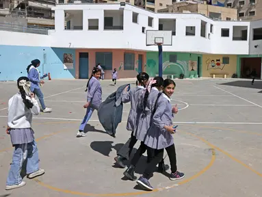 Siswi-siswi sekolah Palestina berjalan-jalan di taman bermain sekolah yang dikelola Badan PBB untuk pengungsi Palestina (UNRWA) di kamp pengungsi Shuafat, Yerusalem timur pada 6 Mei 2025. (AHMAD GHARABLI/AFP)