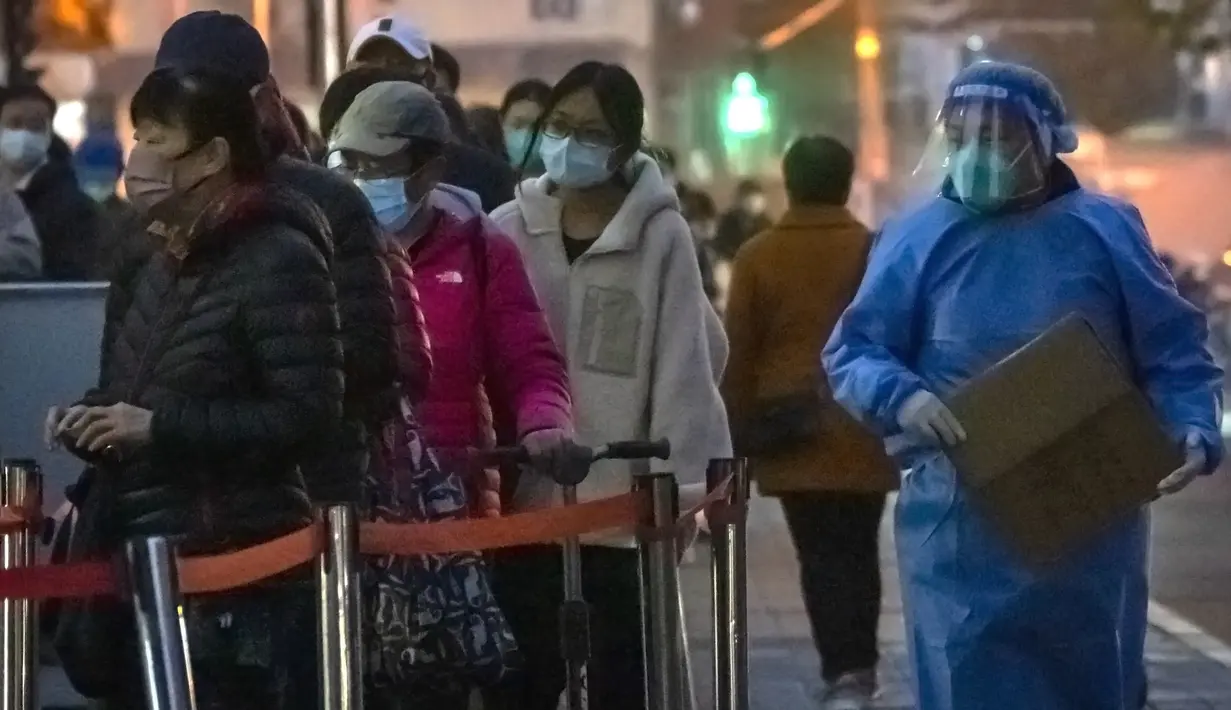 Seorang pekerja yang mengenakan pakaian pelindung berjalan melewati orang-orang yang mengantri untuk tes COVID-19 di tempat pengujian virus corona di Beijing, Rabu (9/11/2022). Lonjakan kasus COVID-19 telah mendorong penguncian di pusat manufaktur China selatan Guangzhou, menambah keuangan tekanan yang telah mengganggu rantai pasokan global dan secara tajam memperlambat pertumbuhan ekonomi terbesar kedua di dunia itu. (Foto AP/Mark Schiefelbein)