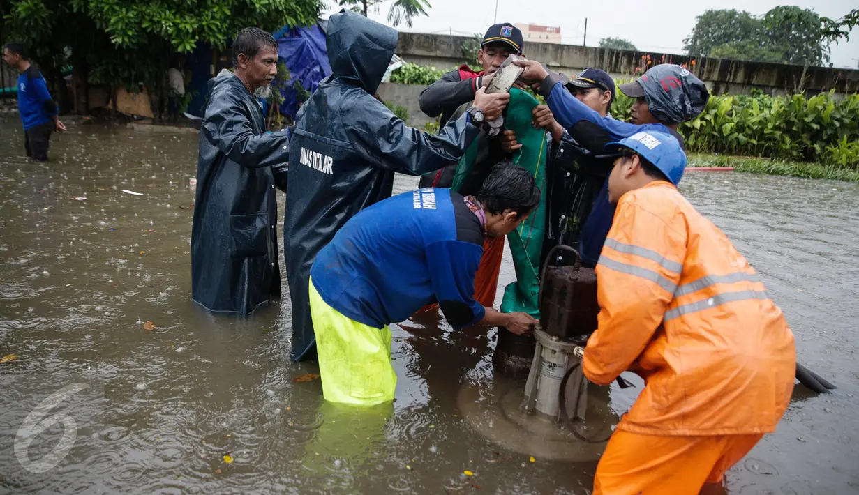 Petugas dari Suku Dinas Tata Air memasang mesin pompa untuk menyedot air banjir yang merendam Jalan Gunung Sahari, Jakarta, Selasa (21/2). Hujan yang mengguyur sejak Selasa dinihari membuat sebagian wilayah di Jakarta banjir. (Liputan6.com/Faizal Fanani)