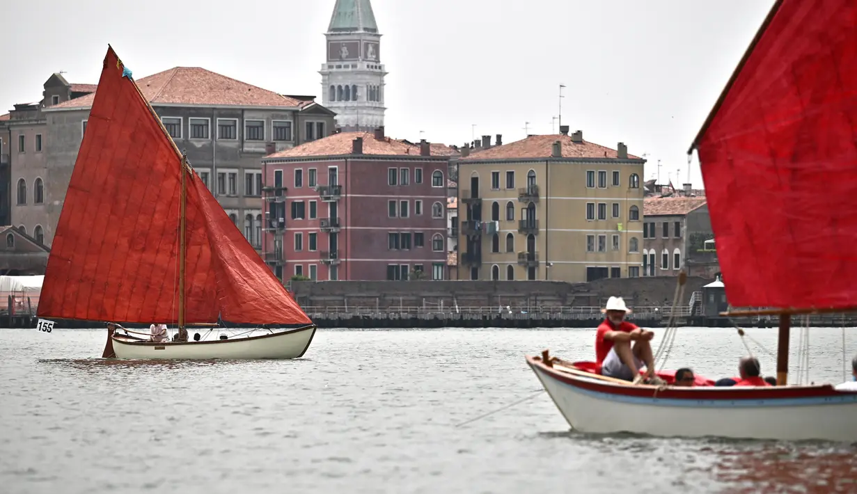 Anggota asosiasi pelayaran budaya berlayar dalam acara Regatta Merah di Venesia, Italia, Minggu (20/6/2021). Acara ini bertujuan untuk merayakan tradisi bahari Venesia kuno dan untuk meningkatkan kesadaran tentang keseimbangan antara kota dan laut. (MARCO BERTORELLO/AFP)