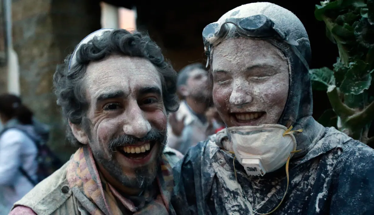 Dua peserta berpose dengan muka yang dipenuhi tepung saat mengikuti Festival O Entroido di Laza, Spanyol, Senin (8/2). Festival yang berlangsung selama seminggu itu dianggap sebagai peristiwa sosial dan budaya utama di kota Laza. (REUTERS/ Miguel Vidal)
