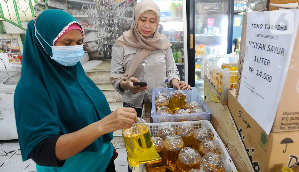 Warga membeli minyak goreng curah di Toko Tjandra, Cinere, depok, Jumat (03/06/2022). Paska dicabutnya kebijakan subsidi minyak goreng curah, pembeli minyak goreng curah di pasaran diwajibkan menyertakan kartu tanda penduduk (KTP) dengan maksimal 1 ktp untuk 2 liter minyak goreng curah seharga Rp 14.000/liter. (merdeka.com/Arie Basuki)