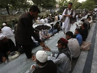 Salah satu petugas memberikan takjil kepada warga yang menunggu waktu berbuka puasa di kota Kabul, Afganistan, (29/6/2014). (REUTERS/Omar Sobhani)