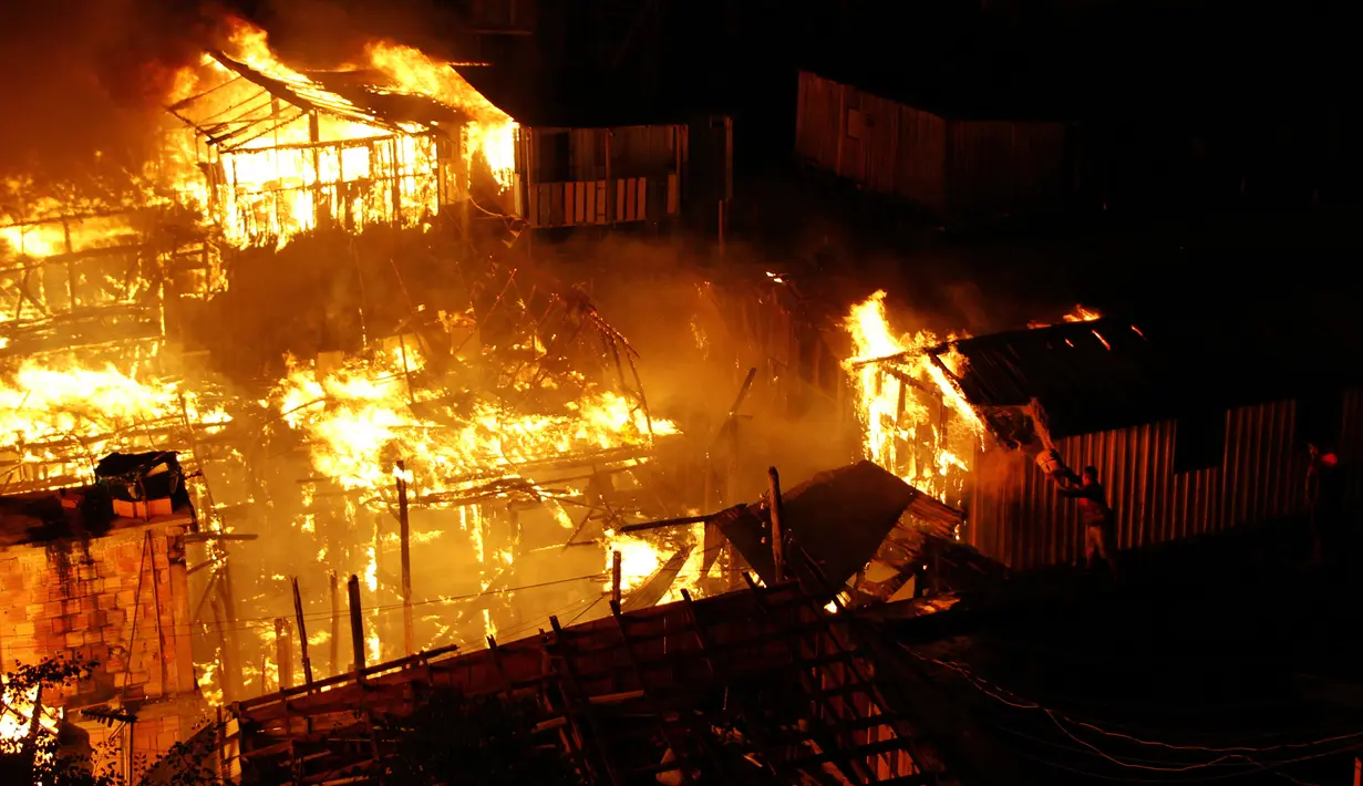 Warga berusaha memadamkan api dengan air saat kebakaran di lingkungan Educandos, di Manaus, Brasil (17/12). Para pihak berwenang mengatakan setidaknya 600 rumah kayu hanggus terbakar. (AP Photo/Edmar Barros)
