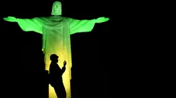 Dekorasi lighting patung Jesus oleh seniman Prancis Gaspare Di Caro beberapa menit sebelum pembukaan Olimpade Rio 2016 di Rio de Janeiro.(AFP/Jeff Pachoud)