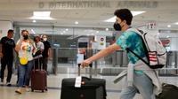 Wisatawan keluar dari pintu kedatangan Internasional di Bandara Miami, Florida, Senin (20/9/2021). Amerika Serikat akan mencabut larangan perjalanan covid-19 pada semua penumpang udara yang sudah divaksin lengkap dan menjalani tes serta pelacakan kontak pada November. (Joe Raedle/Getty Images/AFP)