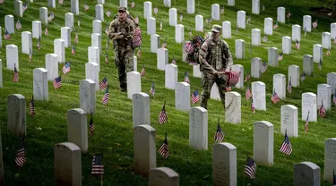 Anggota Resimen Infantri ke-3 Amerika Serikat yang juga dikenal sebagai The Old Guard menempatkan bendera pada setiap nisan untuk aksi "Flags-In" jelang Memorial Day di Pemakaman Nasional Arlington, Arlington, Amerika Serikat, Kamis (25/5/2023). Kegiatan ini untuk menghormati pahlawan militer Bangsa yang gugur. (AP Photo/Andrew Harnik)