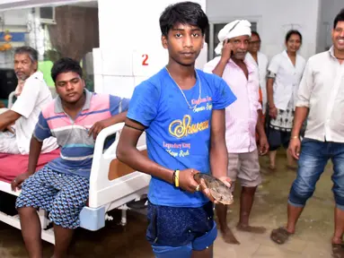 Anggota keluarga pasien yang dirawat, menangkap seekor ikan di dalam bangsal rumah sakit kamar yang tergenang banjir di Nalanda Medical College Hospital, daerah Bihar, India, 29 Juli 2018. Peristiwa unik ini ramai menjadi perbincangan netizen. (AFP PHOTO)