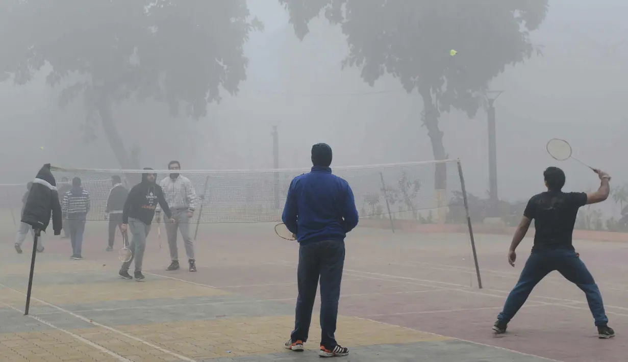 Sejumlah pria bermain bulu tangkis di tengah kabut tebal dan polusi udara di Amritsar, India (2/1). (AFP Photo/Narinder Nanu)