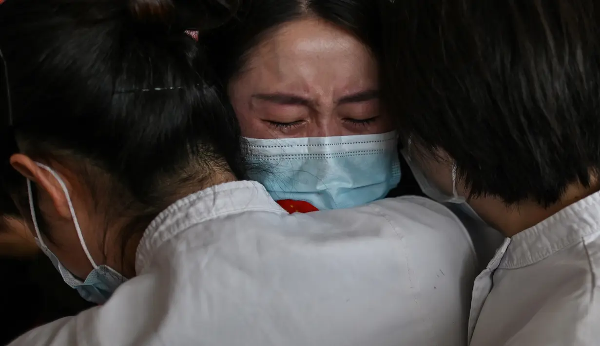 Staf medis dari Provinsi Jilin (tengah) memeluk perawat dari Wuhan setelah bekerja bersama menangani pandemi Covid-19 saat upacara pelepasan di Bandara Tianhe, Wuhan, provinsi Hubei, Rabu (8/4/2020). Pemulangan staf medis ini bersamaan dengan dicabutnya status lockdown Wuhan. (Hector RETAMAL/AFP)