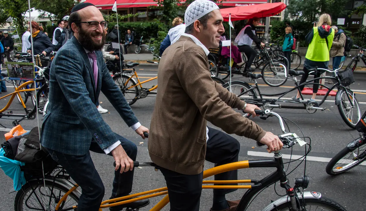 Imam Osman Oers (depan) dan Rabbi Akiva Weingarten mengayuh sepeda tandem sebagai kampanye lintas agama di  Berlin, 24 Juni 2018. Sekitar 25 orang Yahudi dan Muslim yang ikut dalam aksi lintas agama itu diantaranya rabbi dan imam. (AFP/John MACDOUGALL)