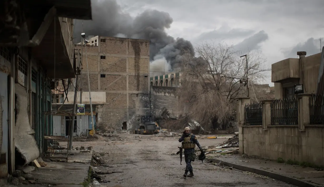 Polisi Irak berjalan sambil berbicara dengan rekannya menggunakan radio saat bertempur melawan militan ISIS di barat Mosul, Irak, 16 Maret 2017. (AP Photo/Felipe Dana)