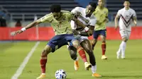 Bek Kolombia, Johan Mojica, berebut bola dengan penyerang Venezuela, Sergio Cordova, pada laga kualifikasi Piala Dunia 2022 zona Amerika Selatan di Estadio Metropolitano, Sabtu (10/10/2020) pagi WIB. Kolombia menang 3-0 atas Venezuela. (AFP/Mauricio Duenas/pool)