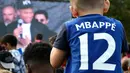 Seorang anak memakai jersey bernama bintang Prancis, Kylian Mbappe, saat jumpa fans markas AS Bondy di Paris, Rabu (17/10). Kunjungan ke klub pertamanya ini dilakukan setelah dirinya meraih gelar Piala Dunia 2018. (AFP/Franck Fife)