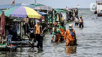Petugas PPSU membersihkan sampah saat terjadi banjir rob di Pelabuhan Kali Adem, Muara Angke, Jakarta, Selasa (9/11/2021). Walau terendam banjir rob, petugas PPSU tetap sigap bersihkan sampah yang mengambang terbawa air laut. (Liputan6.com/Faizal Fanani)