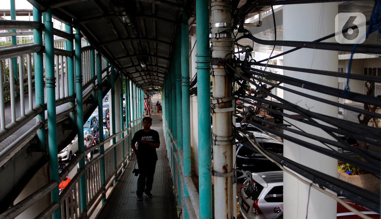 Kondisi kabel utilitas semrawut di dekat jembatan penyeberangan orang (JPO) di Jalan Ciledug Raya, Kawasan Seskoal, Kebayoran Lama, Jakarta, Selasa (8/8/2023). (Liputan6.com/Johan Tallo)