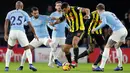 Penyerang Watford, Troy Deeney mengontrol bola dari kawalan tiga pemain Manchester City saat bertanding pada lanjutan Liga Inggris di stadion Vicarage Road (4/12). City menang tipis atas Watford 2-1. (AP Photo/Frank Augstein)