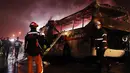 Petugas pemadam kebakaran berusaha memadamkan api yang membakar badan bus di dekat pelabuhan sebelah tenggara Kota Ulsan, Korsel, Kamis (13/10). Bus berisi 20 wisatawan lokal itu terbakar setelah tergelincir dan menabrak pembatas jalan tol. (Yonhap/AFP)