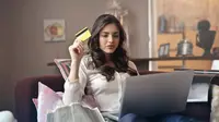 Ilustrasi seorang wanita menggunakan kartu kredit untuk belanja online.