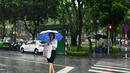 Seorang wanita melintasi jalan saat hujan lebat di Hanoi (14/10/2020). Badai tropis Nangka menghantam Vietnam tengah-utara yang mengakibatkan bencana alam, terutama hujan lebat dan banjir, telah menyebabkan 28 orang tewas dan 12 lainnya hilang. (AFP Photo/Manan Vatsyayana)