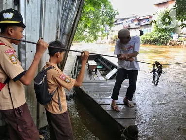 Dua orang pelajar bersiap naik perahu eretan untuk menyeberangi kali Ciliwung di kawasan Manggarai, Jakarta, Rabu (14/5/2025). (Liputan6.com/Angga Yuniar)