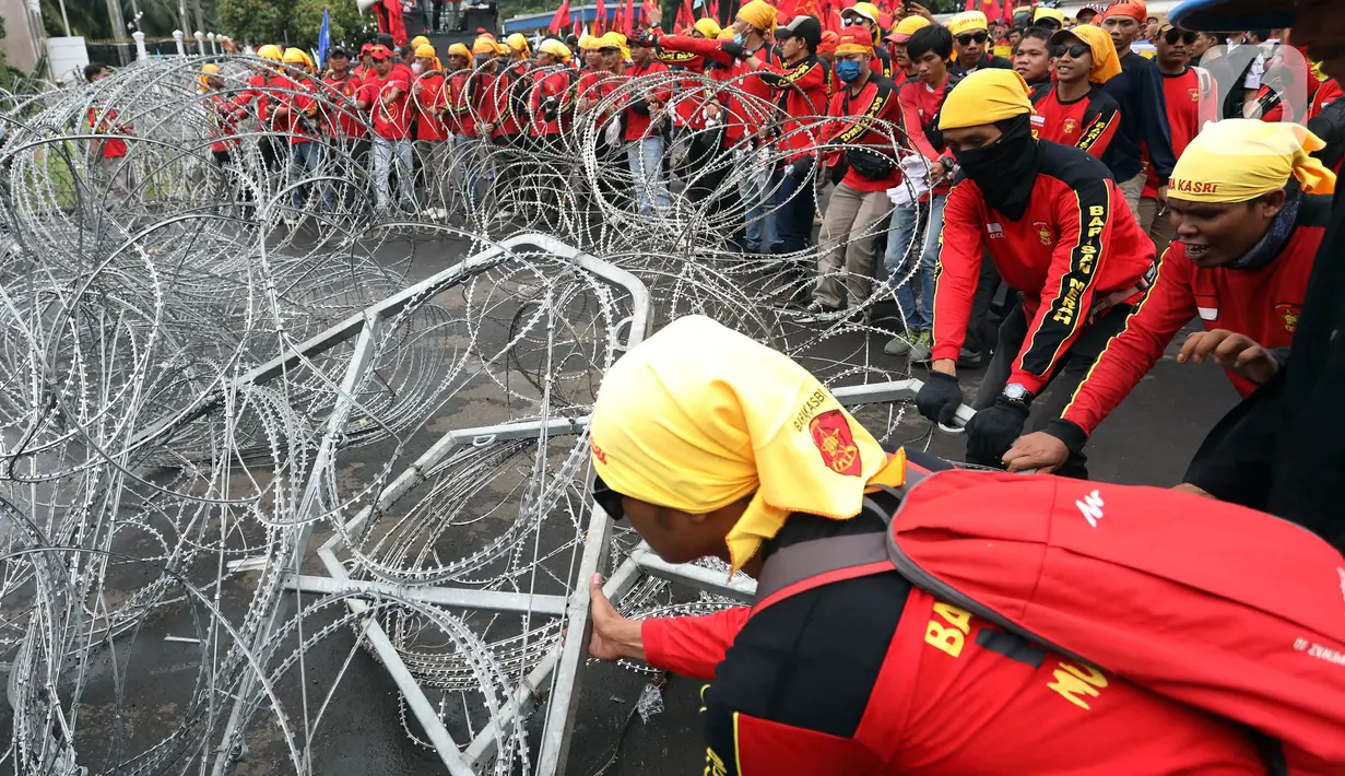 Massa merusak pagar berduri saat berunjuk rasa di depan Gedung DPR, Senayan, Jakarta, Selasa (14/3/2023). Imbas aksi demo tersebut, kepolisian mengimbau kepada para pengguna jalan untuk mencari jalan alternatif guna menghindari kemacetan. (Liputan6.com/Johan Tallo)