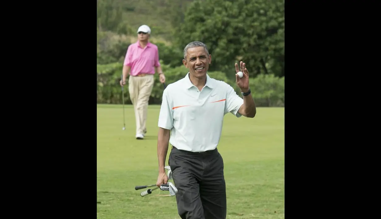 Presiden Amerika Serikat, Barack Obama melambaikan tangan saat bermain golf bermasa PM Malaysia di Hawaii, Rabu (24/12/2014). (AFP PHOTO/Nicholas KAMM)
