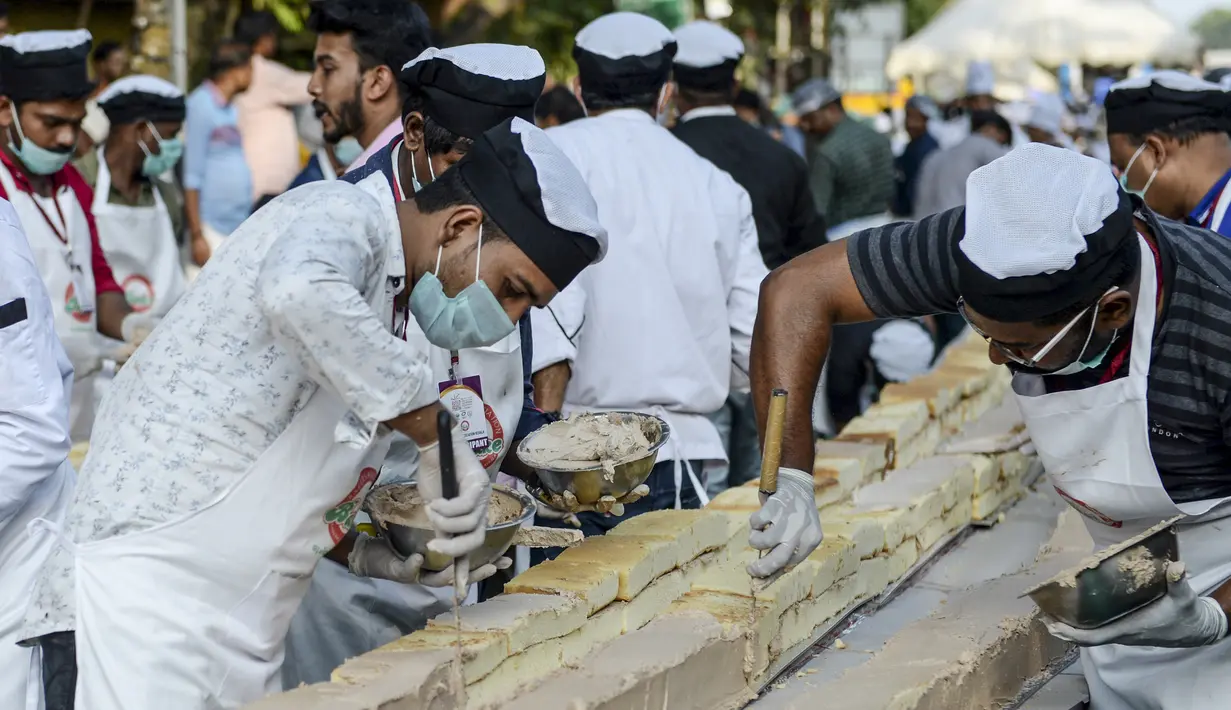 Pembuat roti dan koki menyelesaikan kue sepanjang 6,5 km untuk kue terpanjang dunia, di Thrissur di negara bagian Kerala, India selatan (15/1/2020). Dibutuhkan 12 ribu kilogram gula dan tepung dan menghabiskan waktu lebih dari empat jam untuk membuat kue terpanjang itu. (AFP/Arun Sankar)