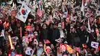 Para pendukung Yoon Suk Yeol melambaikan bendera Korea Selatan dan Amerika Serikat dalam sebuah unjuk rasa di dekat kediaman presiden di Seoul pada tanggal 8 Maret 2025, setelah iring-iringan mobil yang membawa Yoon tiba di kediaman tersebut. (Jung Yeon-je/AFP)