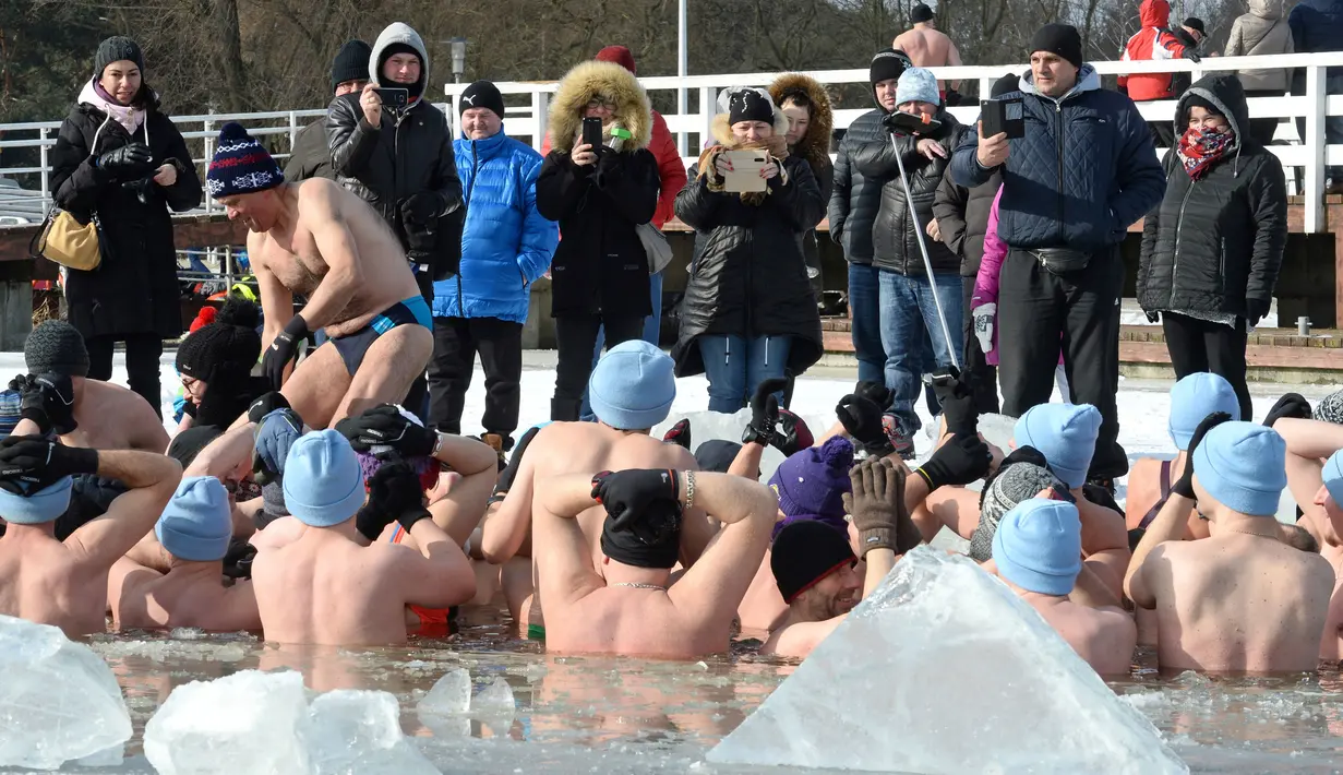 Orang-orang mengambil gambar penggemar renang es di Danau Zalew Zegrzynski di Nieporet, Polandia, Minggu (25/2). Kini, Polandia bersuhu -8 derajat Celsius pada siang dan turun ke -16 derajat Celcius di malam hari. (AP Photo/Alik Keplicz)