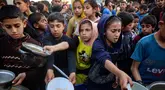 Anak-anak Palestina mendapatkan bagian dari makanan berbuka puasa untuk keluarga mereka di sebuah titik distribusi makanan gratis di kamp pengungsi Nuseirat, Jalur Gaza tengah, pada 14 Maret 2025. (Eyad BABA/AFP)