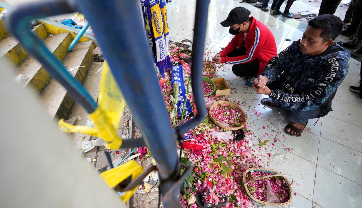Orang-orang berdoa untuk para korban kerusuhan di depan Gerbang 13, Stadion Kanjuruhan, Malang, Selasa (4/10/2022). Polri menjatuhkan sanksi kepada 10 anggota polisi dan menyelidiki 18 orang lainnya buntut tragedi kerusuhan yang menewaskan 125 orang di Stadion Kanjuruhan. (AP Photo/Achmad Ibrahim)
