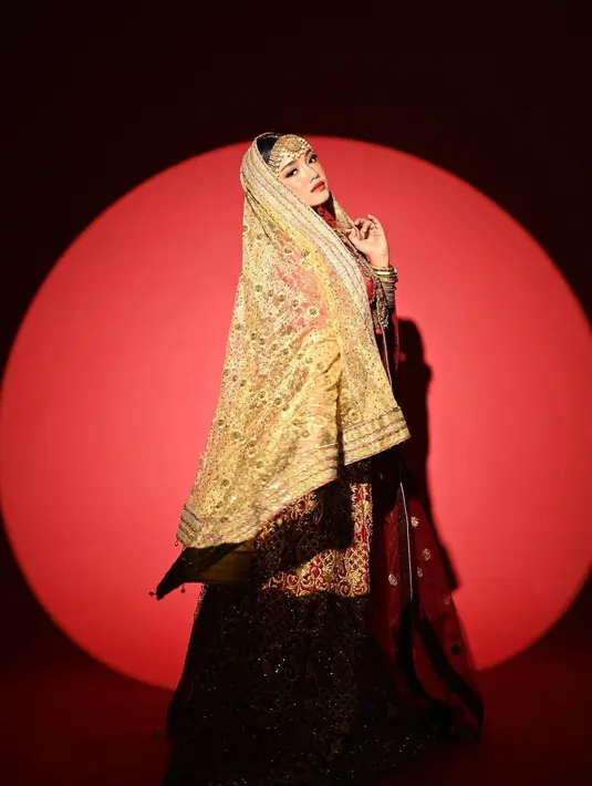 Mengenakan kain sari berwarna dasar merah dengan ornamen keemasan. Inilah yang bikin penampilan Fuji menyiratkan kesan mewah berkali lipat. Belum lagi deretan gelang emas di tangan kanan dan kiri, plus latar merah polos yang ditembak lampu dengan efek membentuk lingkaran. Fuji benar-benar di-highlight Rio Motret. Efeknya glamor sekaligus dramatis. (Foto: Dok. Instagram @riomotret)