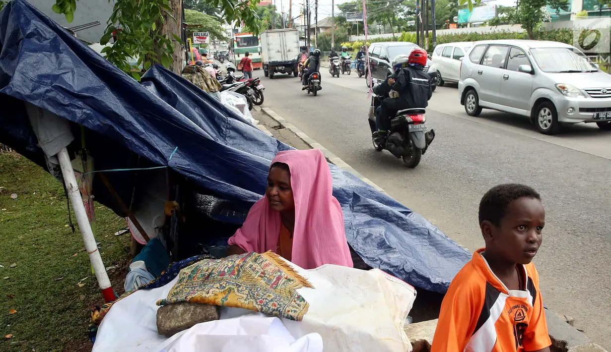 Para pencari suaka berteduh di bawah terpal di trotoar depan Rumah Detensi Imigrasi Kalideres, Jakarta, Jumat (19/1). Para pencari suaka berasal dari Afghanistan, Sudan, dan Somalia. (Liputan6.com/JohanTallo)
