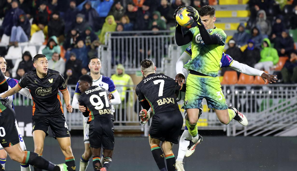 Pemain Venezia, Jay Idzes (kiri) melihat kiper Filip Stankovic berebut bola dengan pemain Hellas Verona dalam laga lanjutan Liga Italia 2024/2025 di Venice, Italia, Selasa (28/01/2025) dini hari WIB. (AP Photo/LaPresse/Paola Garbuio)