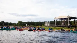Para penonton menikmati konser musik Laivā dari atas perahu di Danau Juglas, Riga, Latvia, 14 Agustus 2021. Warga Latvia bisa menikmati konser musik dari atas kayak, sampan, dan kapal motor bahkan ketika mereka belum divaksin COVID-19. (Gints Ivuskans/AFP)