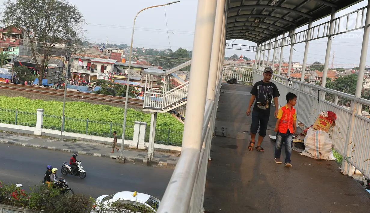 Pejalan kaki melintasi jembatan penyeberangan orang di Jakarta, Minggu (6/8). Dinas Bina Marga DKI Jakarta pada tahun ini akan merevitalisasi JPO yang sudah tua di Ibu Kota. (Liputan6.com/Immanuel Antonius)