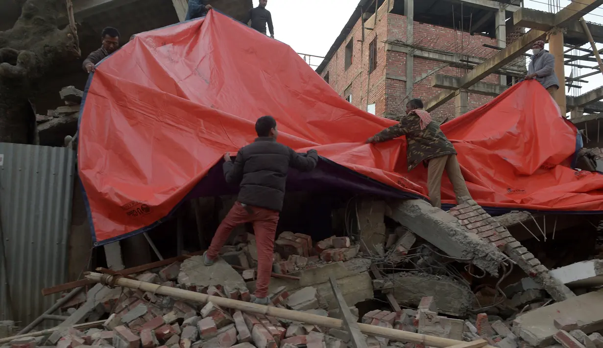 Warga menggunakan terpal untuk menutup bangunan yang rusak di Imphal setelah gempa bumi 6,7 SR mengguncang timur laut India, Senin (4/1). Delapan orang tewas sementara lebih dari 100 orang menderita luka-luka akibat gempa. (AFP PHOTO/Dibyangshu Sarkar)