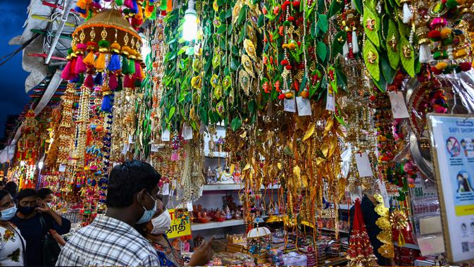 Orang-orang berjalan melintasi sepanjang toko yang menjual ornamen dan dekorasi menjelang Diwali, festival cahaya bagi umat Hindu, di distrik Little India di Singapura pada 23 Oktober 2020. (Photo by Roslan RAHMAN / AFP)