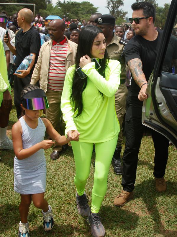 Kim Kardashian dan sang putri, North West menuju sebuah kendaraan setelah bersama suaminya, Kanye West mengunjungi Kampung Anak UWESCO di Masulita, Uganda, Selasa (16/10). UWESO merupakan desa untuk menampung anak-anak yatim piatu. (AP/Stephen Wandera)