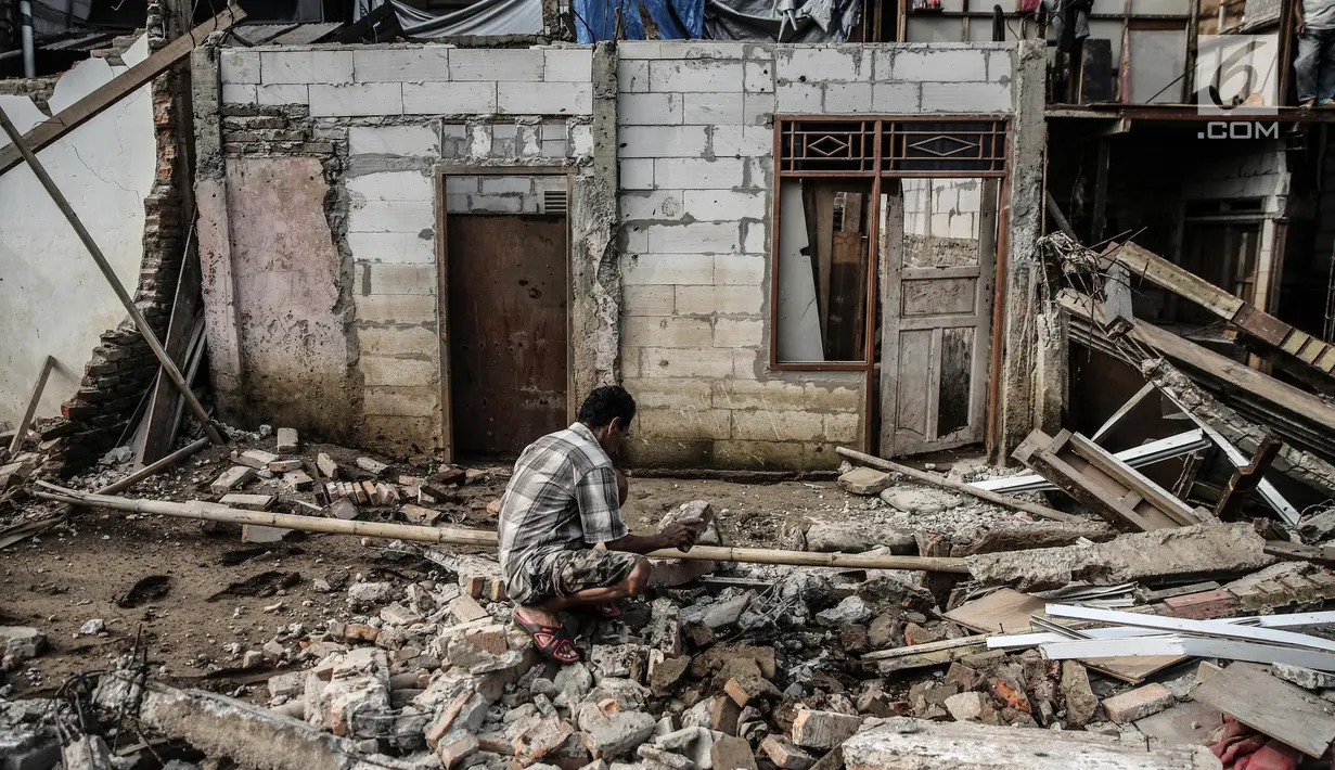 Warga mengumpulkan kayu dari puing-puing sisa penertiban bangunan di bantaran Sungai Ciliwung, kawasan Bukit Duri, Jakarta Selatan, Selasa (11/7). Terdapat 355 bangunan yang ditertibkan guna menanggulangi banjir di Jakarta ini (Liputan6.com/Faizal Fanani)